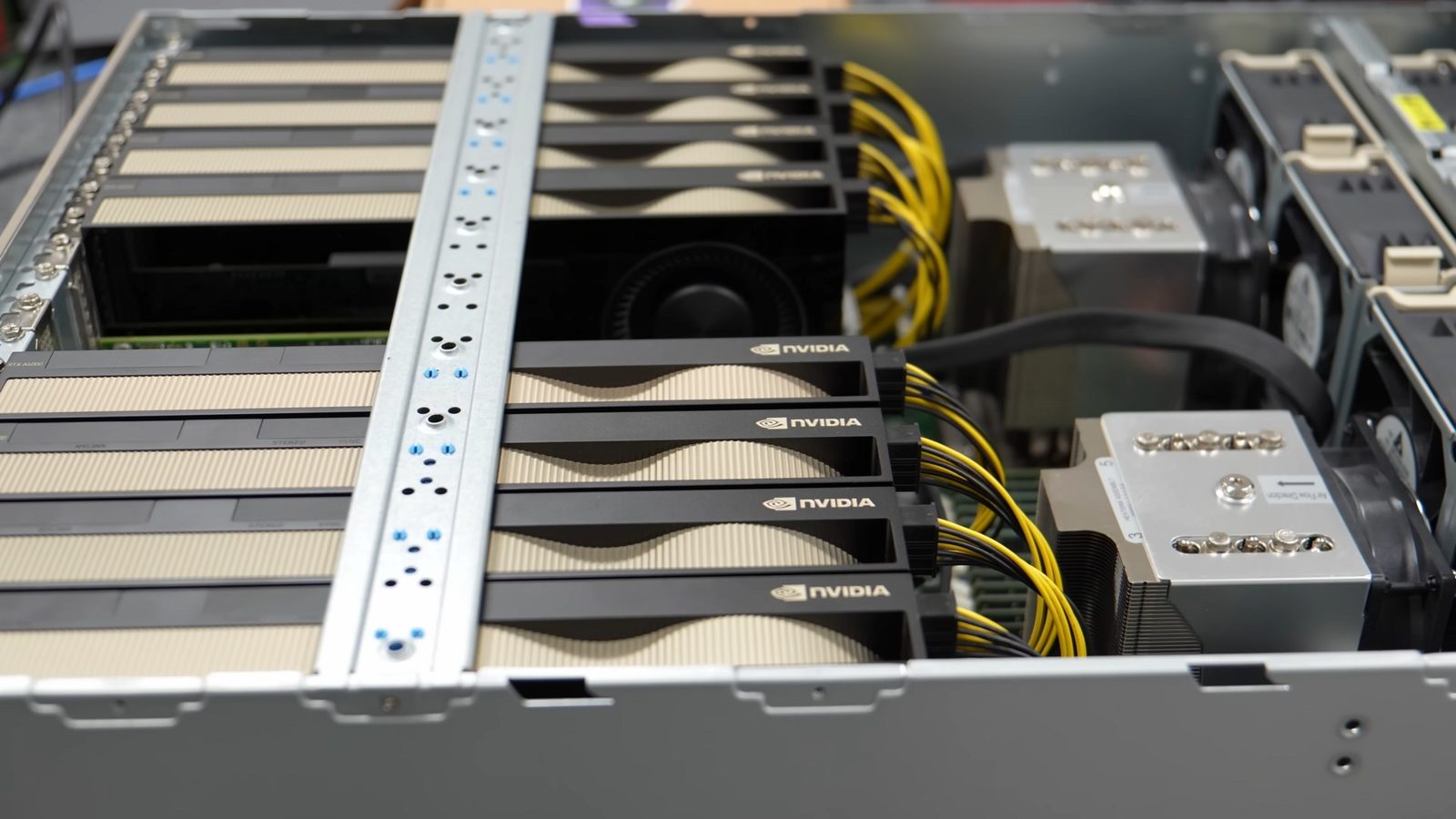 An open Supermicro GPU server with a row of NVIDIA graphics cards, power cables and AMD EPYC processor coolers
