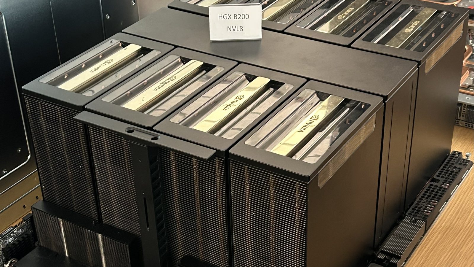 An NVIDIA HGX B200 board with eight GPUs under large black heatsinks, with a card on top reading HGX B200 NVL8