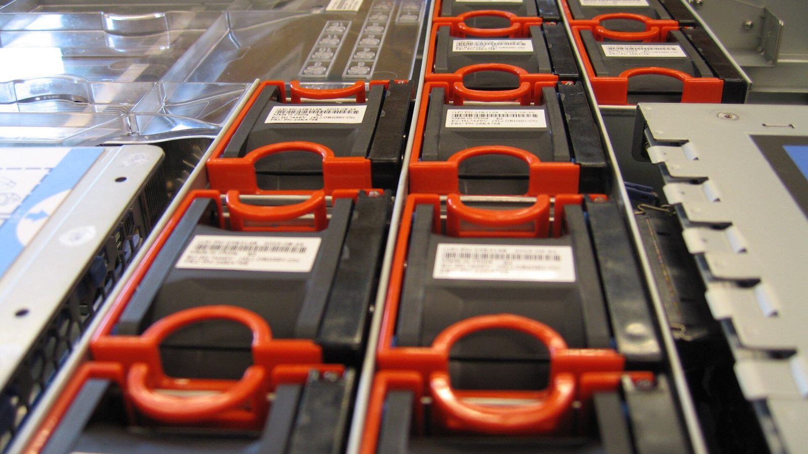 A row of hot-swap server fans with orange handles inside an open rack server