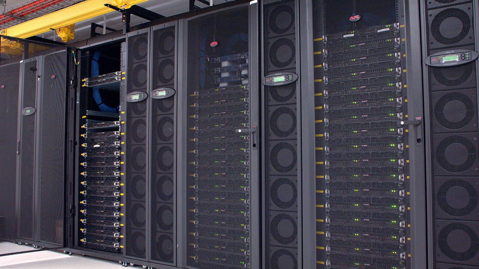 Rows of black server racks with green status lights and in-row cooling units in the CSIRO GPU cluster data centre